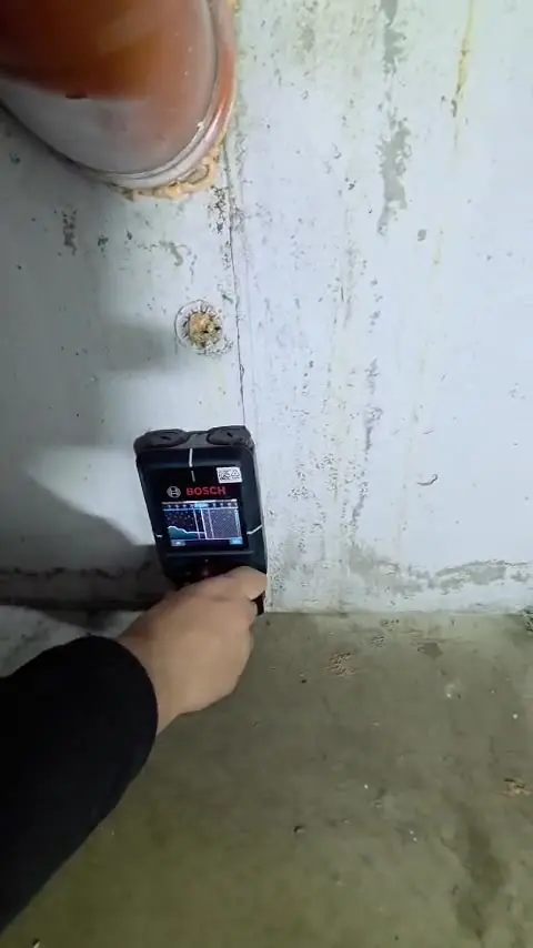 Detector de zone umede ținut pe un perete de beton