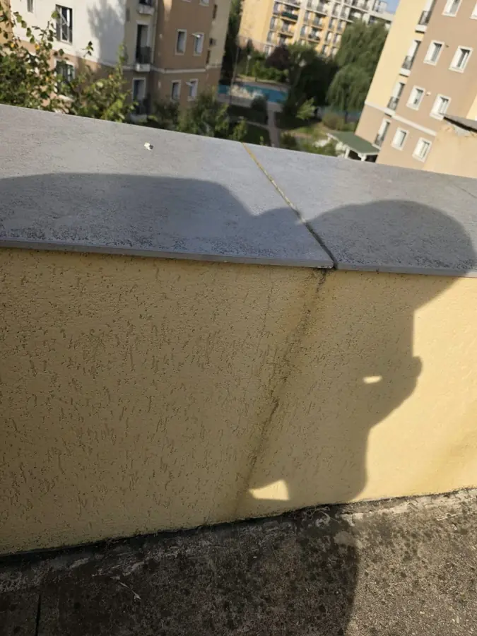 Dungi închise pe tencuiala unui parapet, sub rosturile coronamentului