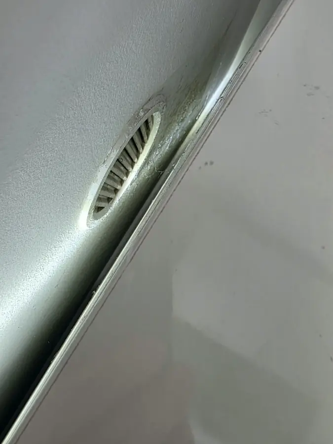Mucegai pe muchia unui panou, lângă o grilă de aerisire