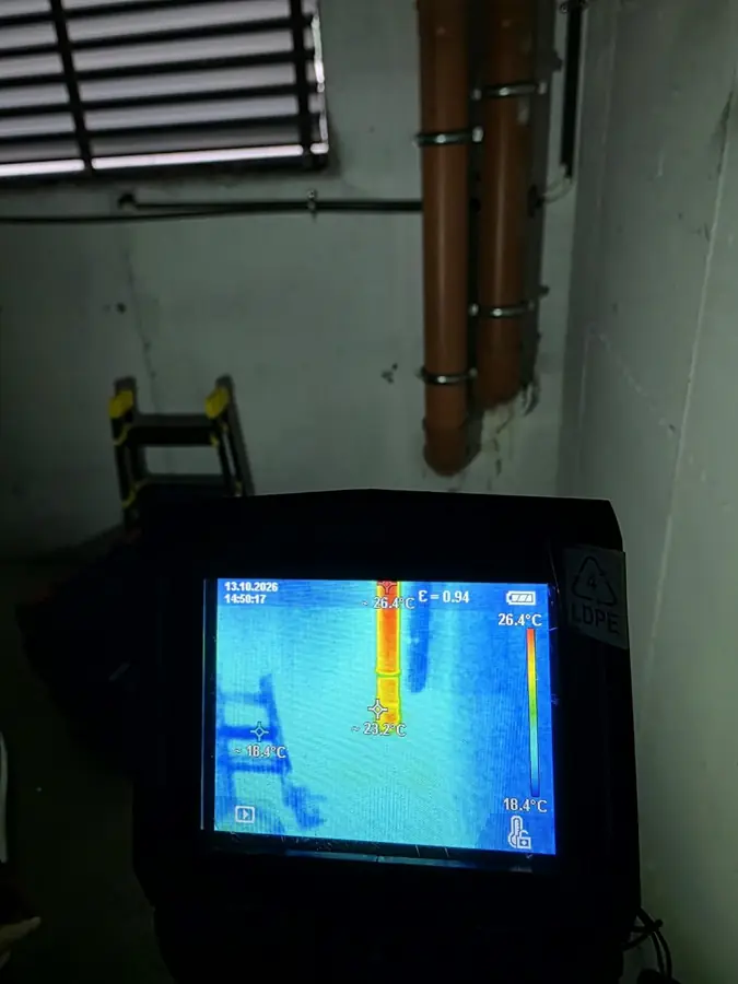 Camera termografică ținută în fața unui perete cu țevi de canalizare